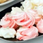 White and red swirl peppermint meringue cookies on a silver tray.