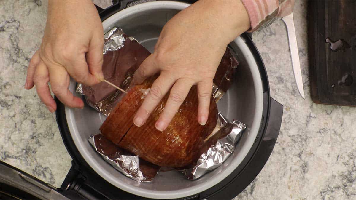 securing last slice of ham with a toothpick before cooking.