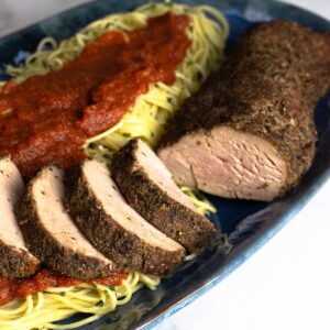 smoked pork loin sliced on a bed of angel hair pasta with marinara sauce.