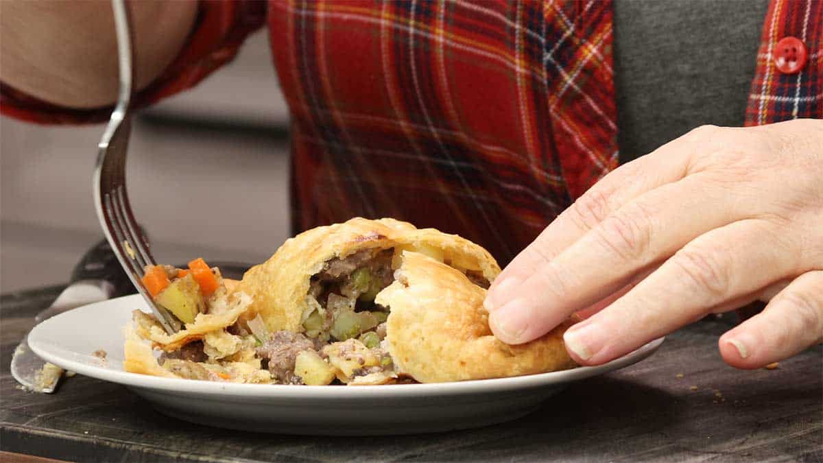 Savory hand pie cut in half and digging in with a fork to eat it. 