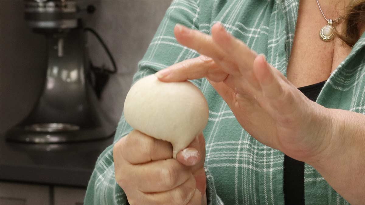 squeezing dough ball to form tension.