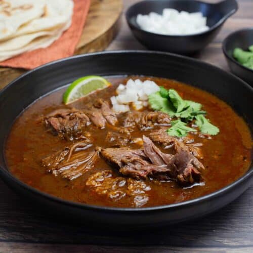 Large bowl of birria stew with garnishes.