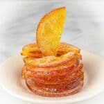 Stacked candied orange slices on a white plate.
