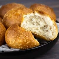 French bread dinner rolls in a bowl with a tea towel and the front one is open to see inside the roll.