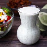 Homemade Ranch Dressing in a glass pouring container next to a side salad.