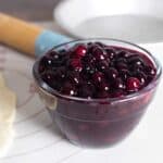 bowl of homemade blueberry pie filling sitting next to a rolled out pie crust.