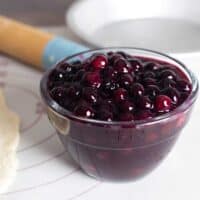 bowl of homemade blueberry pie filling sitting next to a rolled out pie crust.