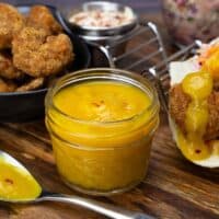 jar of mango sauce next to shrimp tacos.