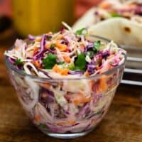 Cilantro Lime Slaw in a glass bowl next to shrimp tacos.