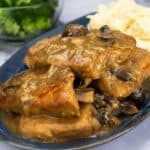 Pressure Cooked Pork Chops on blue platter with gravy and mashed potatoes.
