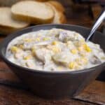 Slow Cooker Chicken Corn Chowder in bowl with sliced Italian bread behind it.