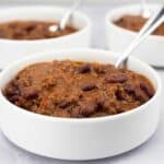 Pork and Beef Chili in a white bowl with 2 bowls behind it.