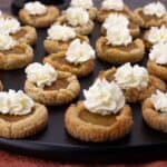 Pumpkin Pie Cookies on black serving tray with a dollop of whipped cream on top of each one.