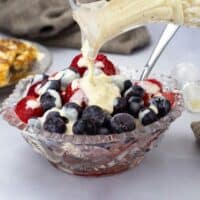 Vanilla Sauce being drizzled over fresh blueberries and strawberries.