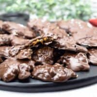 Black tray of pecan caramel clusters with one open showing soft caramel in the center.