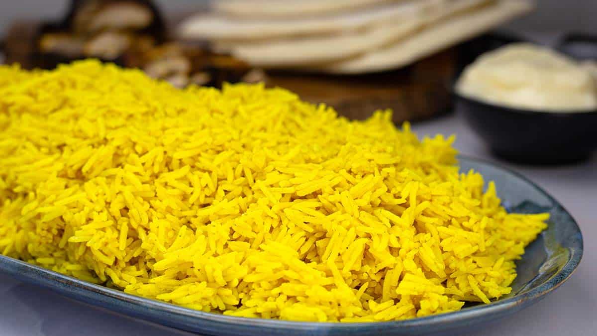 yellow basmati rice in a serving dish with shawarma wraps beside the dish.