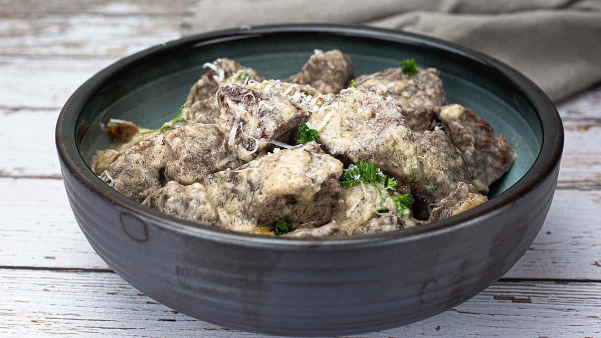 Garlic Parmesan bites in a dark bowl sitting on a table.