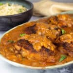 Chicken Paprikash on a platter with a bowl of nokedli noodles behind it.