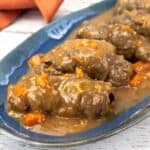 Beef Rouladen with gravy on a blue serving platter.