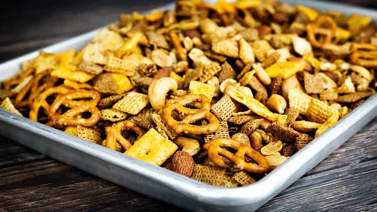 Homemade Chex Mix in Ninja Foodi Possible Cooker Pro with golden brown cereal, nuts and crackers.