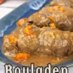 Beef Rouladen on a blue serving tray with gravy and carrots.