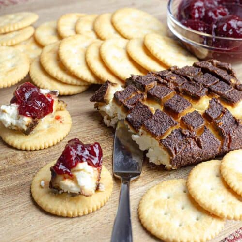 Smoked Cream Cheese on a wood board with crackers and cranberry jelly.