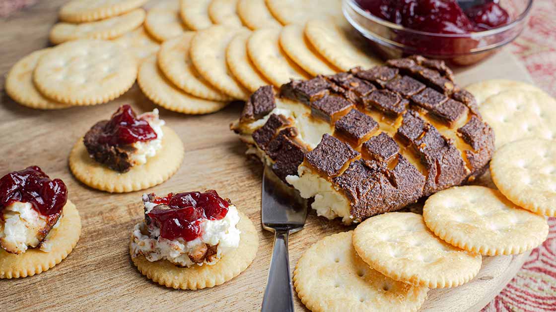 Smoked Cream Cheese on a wood board with crackers and cranberry jelly.