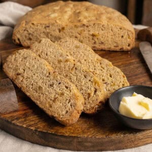 Cinnamon Raisin Quick Bread sliced on a wood platter with butter
