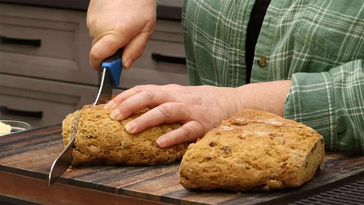 Slicing into Cinnamon Raisin Quick Bread showing the soft, tender interior with golden raisins.