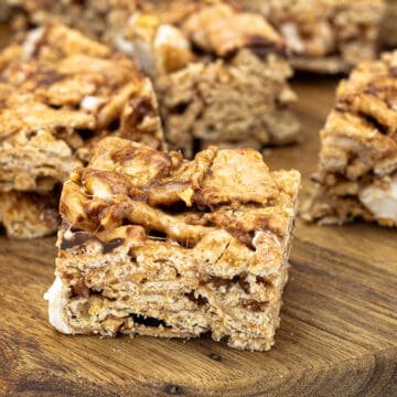 Cinnamon Toast Crunch bars cut into squares and arranged on parchment paper, showing their golden cereal texture and chewy marshmallow layers
