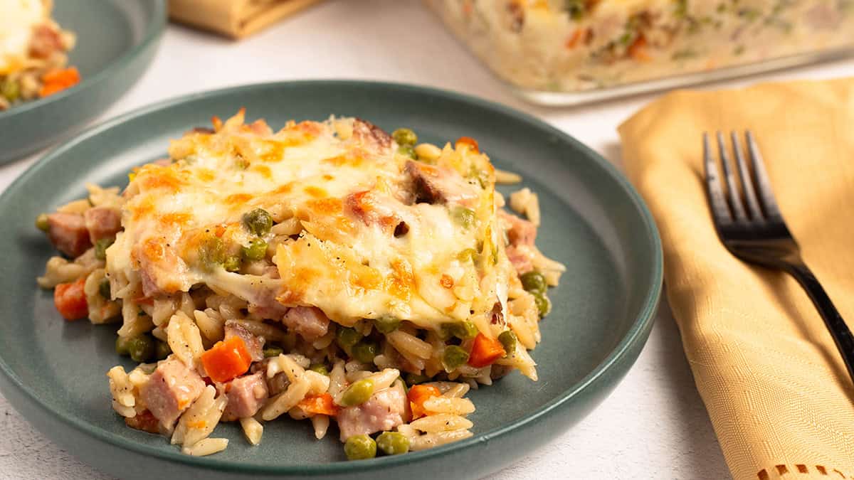 Ham and cheese pasta bake topped with bubbly golden cheese on a teal dinner plate