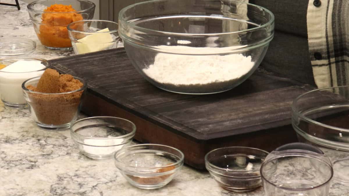 Ingredients for Glazed Pumpkin Bread in glass bowls: flour, pumpkin puree, butter, brown sugar, granulated sugar, baking powder and spices.
